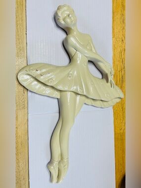 Chalk ware ballerina hangs on the wall.